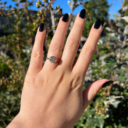 Yellow gold bezel-set round brilliant hearts & arrows cut moissanite or lab diamond solitaire engagement ring shown on a model's finger.