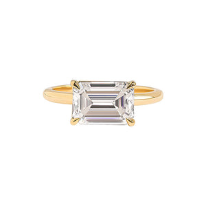 East-west emerald cut solitaire engagement ring in yellow gold.