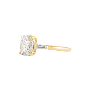 Oval yellow gold engagement ring with tapered baguette lab diamonds.
