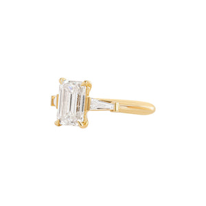 Yellow gold engagement ring set with an emerald cut lab diamond and tapered baguette sides. Cathedral set. 
