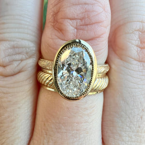 Yellow gold antique inspired wedding band. Striped engraving. Wide band. Stacked on hand with Gaia Oval Lab Grown Engagement Ring.