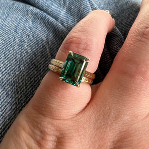 Yellow gold emerald cut engagement ring, with hand wheat engraving inspired by the Art Deco period. Stacked on hand with Yara band.