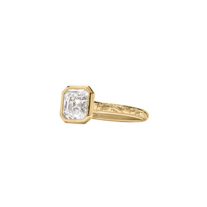 Yellow gold Asscher cut bezel engagement ring with a hand engraved floral band. Side angled view.