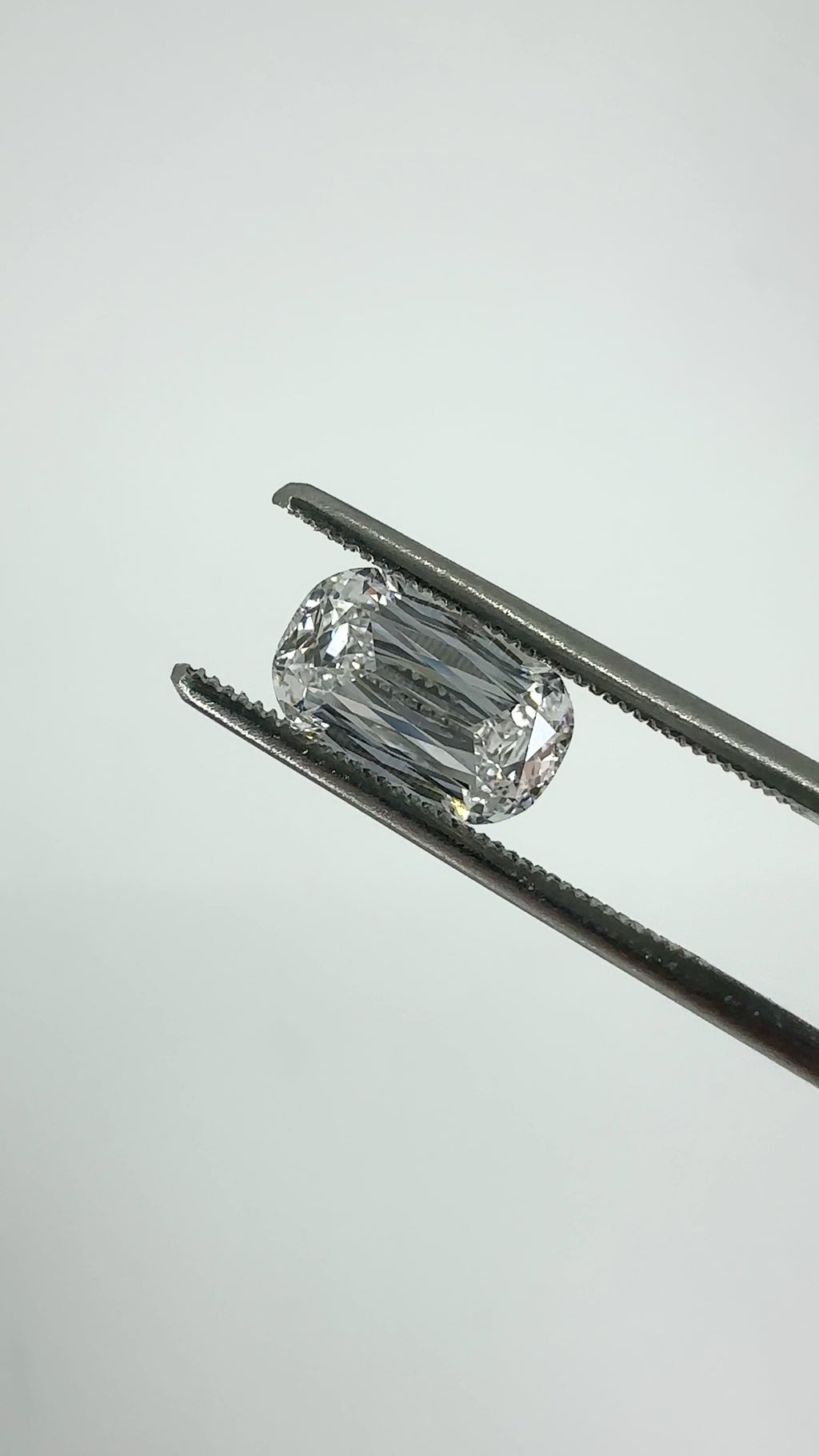 cushion scissor cut diamond held in tweezers