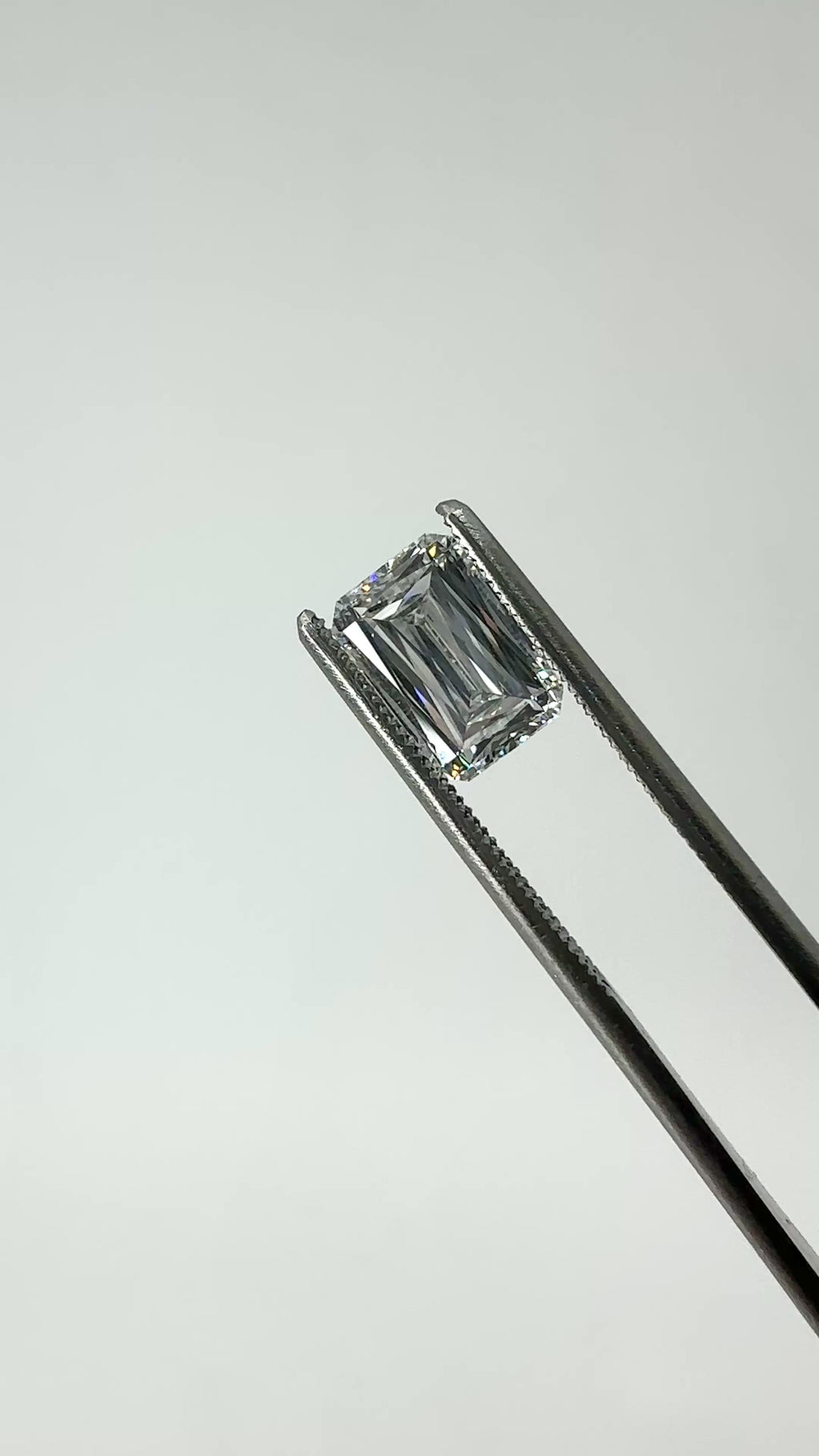 scissor cut emerald diamond held in tweezers