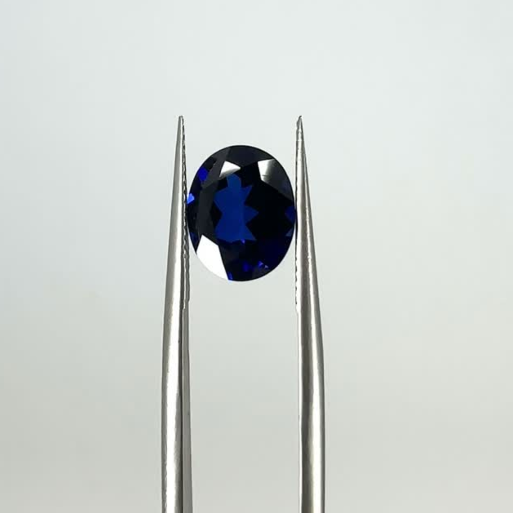 video of an oval blue sapphire on tweezers