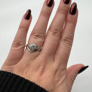 White gold old European or round brilliant accented engagement ring. Eight-prong Victorian crown basket. Diamond accented side triangles. Floating gallery cathedral. Stacked on hand with V Band.