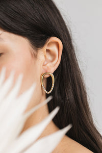 Yellow gold earring shaped like a soda tab with lab diamonds flush set into the bottom half of the earring.