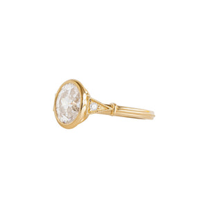 Yellow gold bezel-set antique-inspired oval engagement ring on a white background. Ring has hand-carved milgrain on the bezel and side triangles with accent lab diamonds. Integrated basket, antique fluting on shank. Side view.