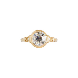 Yellow gold bezel-set antique-inspired Old European Cut round engagement ring on a white background. Ring has hand-carved milgrain on the bezel and side triangles with accent lab diamonds. Integrated basket, antique fluting on shank. Front view.