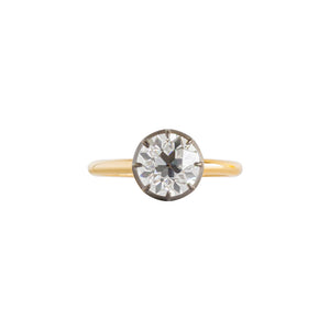 Black bezel Georgian collet setting engagement ring holding an Old European Cut round moissanite or lab diamond on a white background. Yellow gold band. Front view.