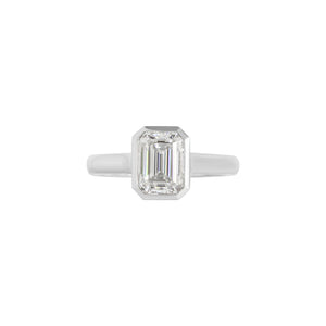 White gold bezel-set emerald cut moissanite or lab diamond solitaire engagement ring on a white background. Floating gallery cathedral. Front view.