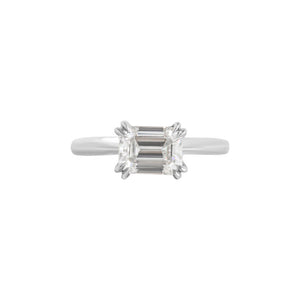 White gold East-West set emerald cut moissanite or lab diamond solitaire engagement ring on a white background. Features double claw prongs, a knife edge band and an integrated basket. Front view.