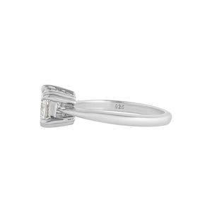 White gold East-West set emerald cut moissanite or lab diamond solitaire engagement ring on a white background. Features double claw prongs, a knife edge band and an integrated basket. Side view.