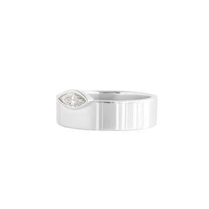 Asymmetrical white gold engagement ring or wedding band on a white background. East-west marquise moissanite or lab diamond offset onto a wide band. Side view.