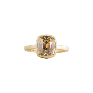 Yellow gold bezel-set engagement ring with hand-carved milgrain and integrated basket, on a white background. Set with a brown Old Mine Cut or antique cushion moissanite or lab diamond. Front view.
