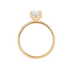 Yellow gold moissanite or lab diamond oval cut engagement ring with lab diamond pave and antique engraving on a white background. Peg head setting. Gallery view.