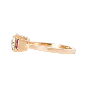 Yellow gold engagement ring with four claw prongs and vertical lab grown ruby baguettes, set with an Old European Cut moissanite or lab diamond. Side view.