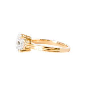 Yellow gold engagement ring with four claw prongs, set with an Asscher cut moissanite and a grooved ridged band.Yellow gold Asscher moissanite or lab diamond engagement ring on a grooved band with ridges, on a white background. Integrated basket. Side view. 