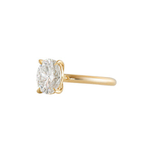 Yellow gold four-prong classic solitaire peg head oval moissanite or lab diamond engagement ring on a white background. Side view.