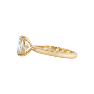 Yellow gold four-prong classic solitaire peg head oval moissanite or lab diamond engagement ring on a white background. Side view.