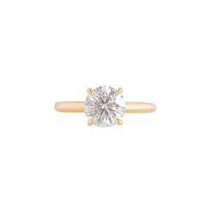 Yellow gold four-prong classic solitaire peg head round brilliant hearts & arrows moissanite or lab diamond engagement ring on a white background. Front view.