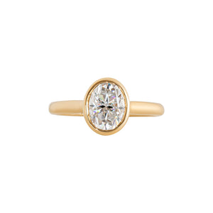 Yellow gold bezel-set oval moissanite or lab diamond solitaire engagement ring on a white background. Floating gallery cathedral. Front view.