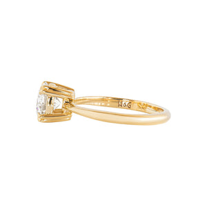 Double claw prong yellow gold round brilliant hearts and arrows cut moissanite or lab diamond solitaire engagement ring on a white background. Knife edge band with an integrated basket. Side view. 