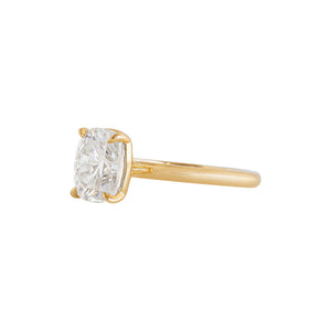 Yellow gold four-prong classic solitaire peg head elongated cushion moissanite or lab diamond engagement ring on a white background. Side view.