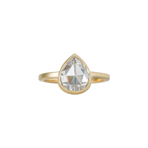 Yellow gold bezel-set engagement ring with hand-carved milgrain and integrated basket, on a white background. Set with a rose cut chubby pear moissanite or lab diamond. Front view. 