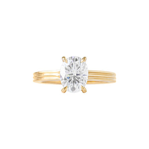 Yellow gold oval moissanite or lab diamond engagement ring on a grooved band with ridges, on a white background. Integrated basket. Front view. 