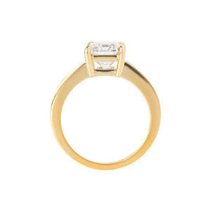 Yellow gold radiant moissanite or lab diamond engagement ring on a grooved band with ridges, on a white background. Integrated basket. Gallery view. 