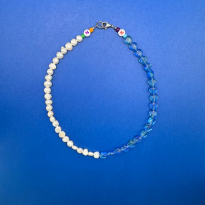 Mixed media pearl and glass necklace with blue beads shaped like scallop shells.